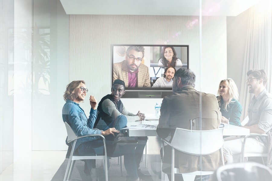 A hybrid meeting is taking place with the Crestron Flex Digital Workplace platform. Five people are in the office, and three more are joining through video call.