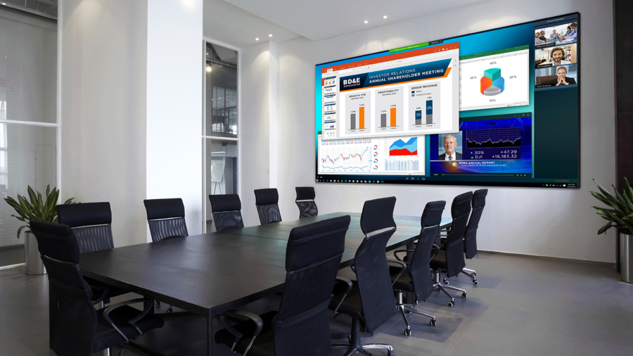 A commercial meeting room with 11 chairs and a display of a large, full-color presentation on a screen with charts.