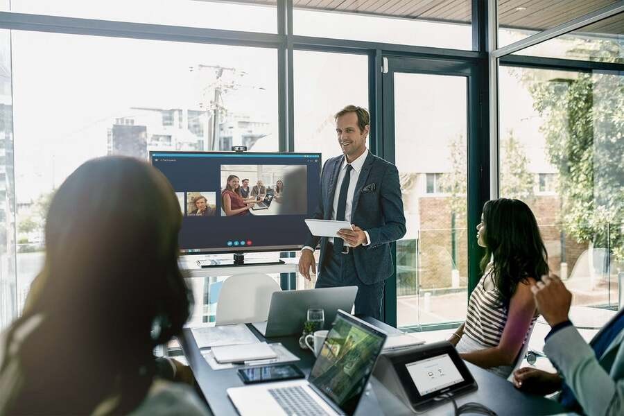 A man shows a presentation during a meeting with his hybrid team using Crestron technology.