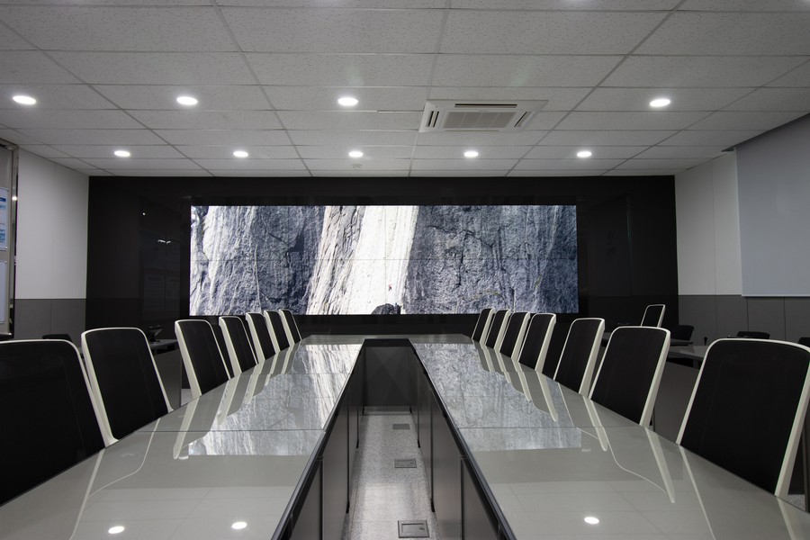 Image is of a conference room table with a gray and white nature image on the screen mounted on the back wall.
